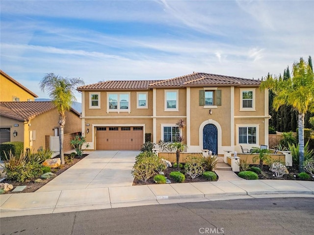 mediterranean / spanish-style home with concrete driveway, an attached garage, and stucco siding