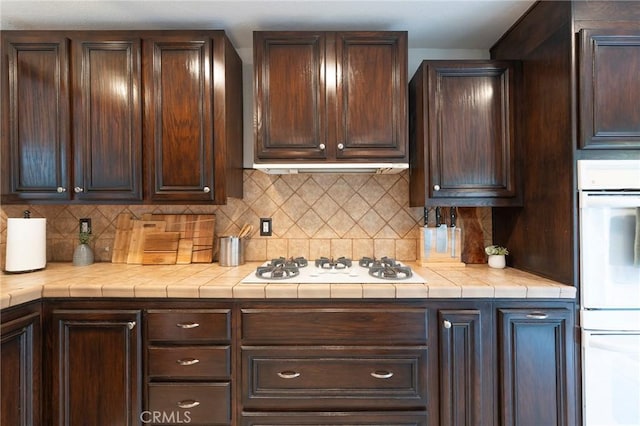 kitchen with backsplash, white gas cooktop, and dark brown cabinets