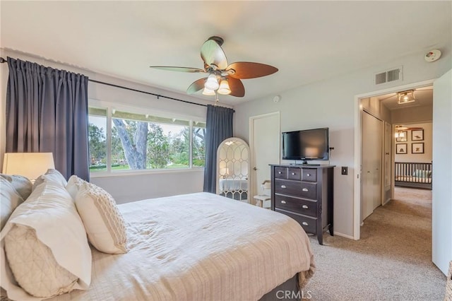 bedroom featuring a ceiling fan, visible vents, and light carpet