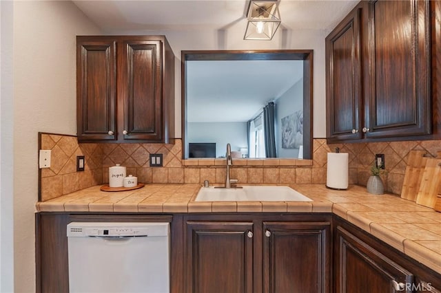 kitchen featuring white dishwasher, a sink, dark brown cabinetry, and decorative backsplash