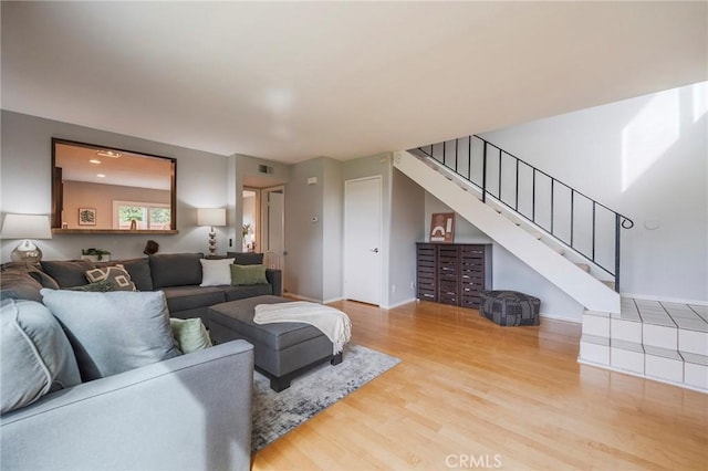 living room featuring baseboards, stairs, visible vents, and wood finished floors