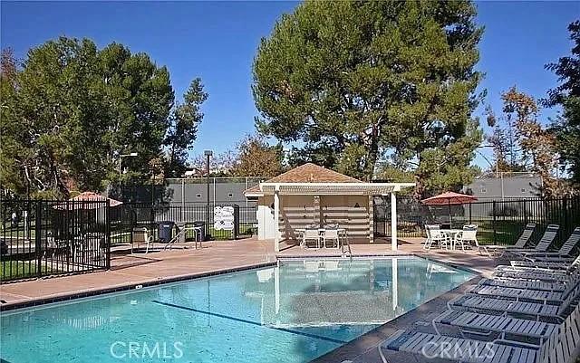 community pool with a patio area and fence