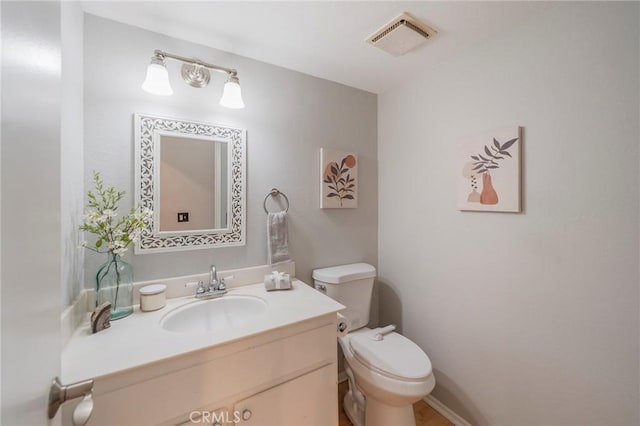 half bath featuring toilet, vanity, and visible vents