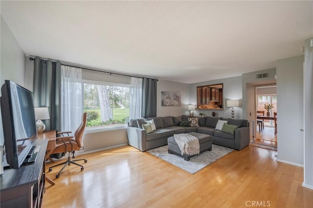 living area featuring light wood finished floors, baseboards, and visible vents