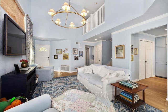 living area featuring a chandelier, visible vents, crown molding, and wood finished floors