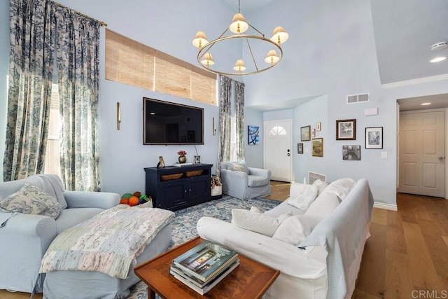 living room featuring baseboards, visible vents, an inviting chandelier, and wood finished floors