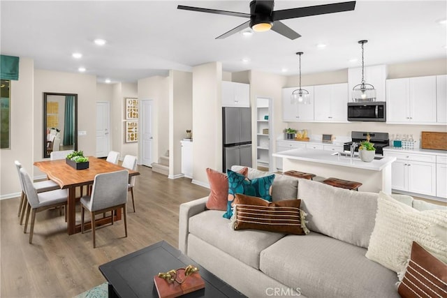 living room featuring recessed lighting, stairway, a ceiling fan, light wood-type flooring, and baseboards