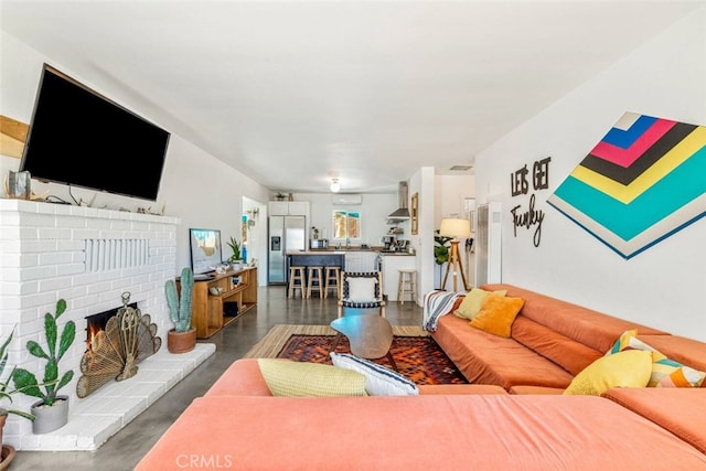 living area featuring concrete floors and a brick fireplace