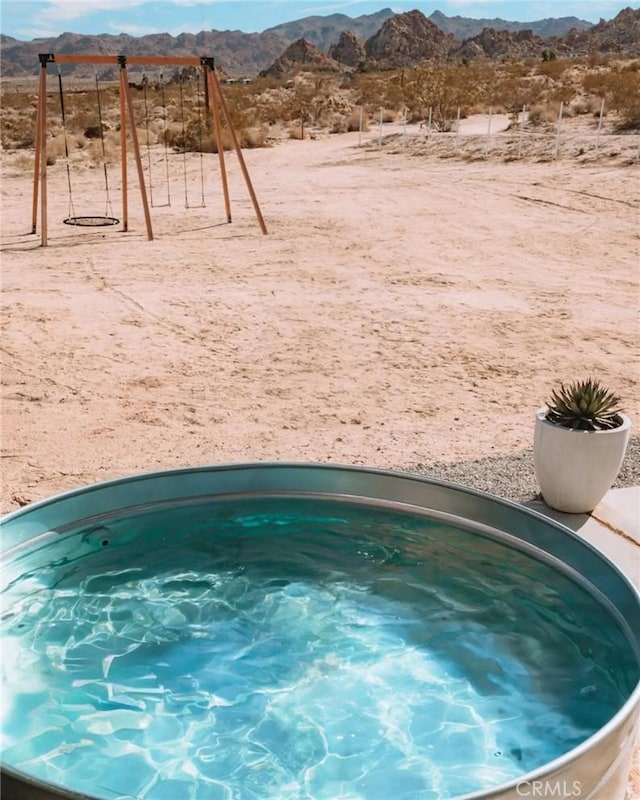 exterior space with a jacuzzi, a mountain view, and playground community