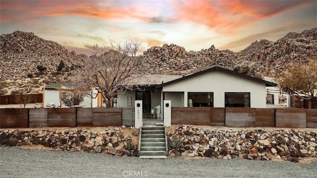 ranch-style home featuring covered porch, fence, and stucco siding