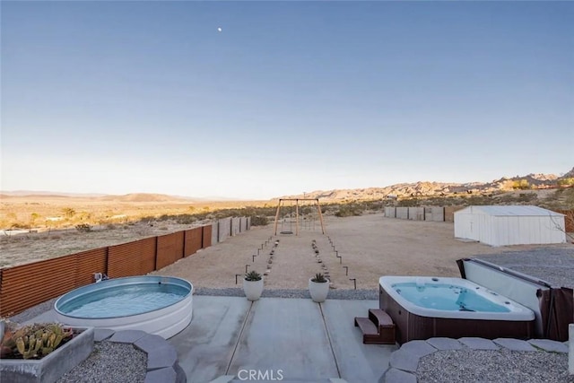 view of yard featuring a fenced backyard, a mountain view, and a hot tub