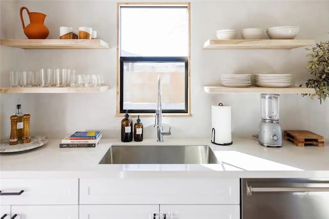 kitchen with open shelves, stainless steel dishwasher, a sink, and light countertops