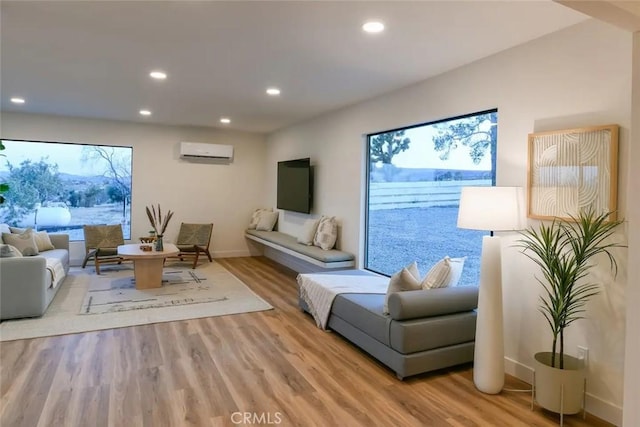 living room with light wood-style floors, recessed lighting, baseboards, and a wall mounted AC