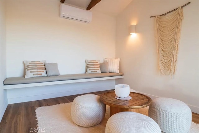 living area featuring baseboards, wood finished floors, and a wall mounted AC