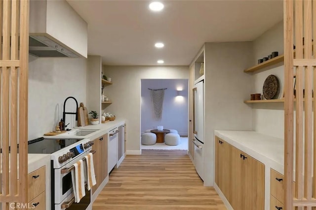 kitchen with open shelves, light countertops, a sink, wall chimney range hood, and white appliances