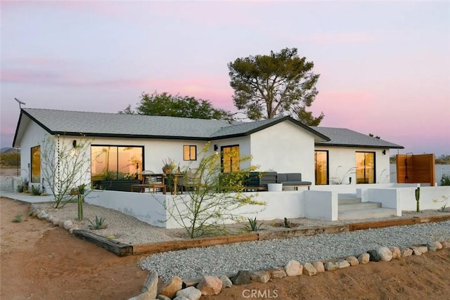 rear view of property featuring an outdoor living space and stucco siding