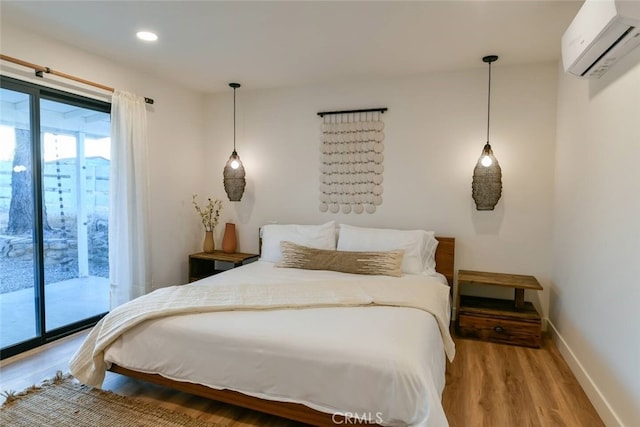 bedroom featuring recessed lighting, an AC wall unit, wood finished floors, access to outside, and baseboards