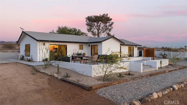 view of front of house featuring a patio, driveway, an attached garage, and stucco siding