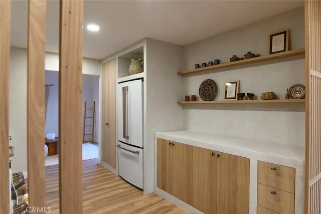 kitchen with light wood-style floors, light countertops, high end white refrigerator, open shelves, and modern cabinets