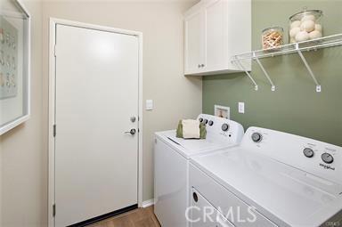 washroom featuring separate washer and dryer, dark wood finished floors, and cabinet space