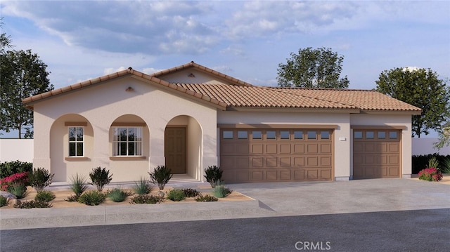 mediterranean / spanish home featuring concrete driveway, an attached garage, a tile roof, and stucco siding