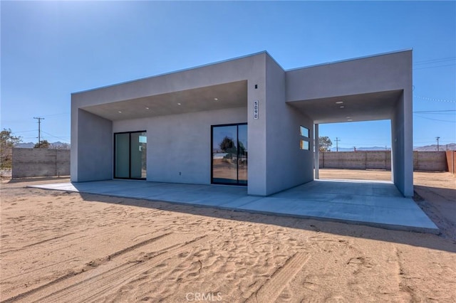 rear view of property with fence, a patio, and stucco siding