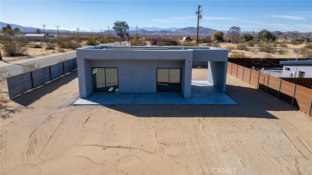 exterior space featuring a patio area, a fenced backyard, a mountain view, and stucco siding