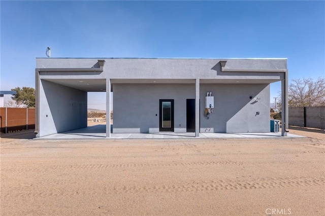 rear view of house featuring fence and stucco siding