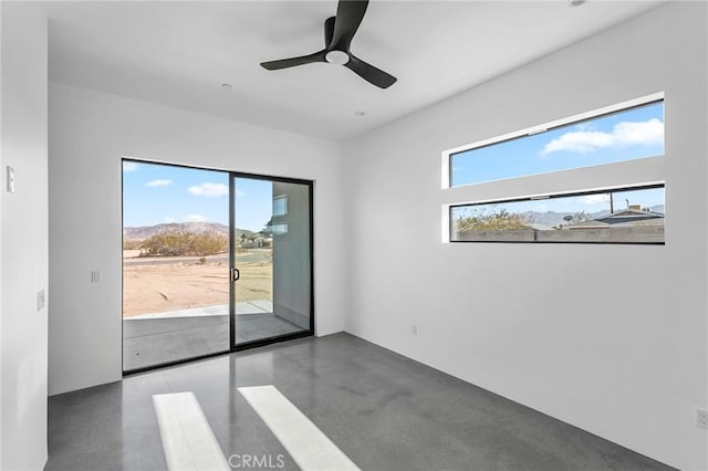 unfurnished room featuring a wealth of natural light, ceiling fan, and finished concrete flooring