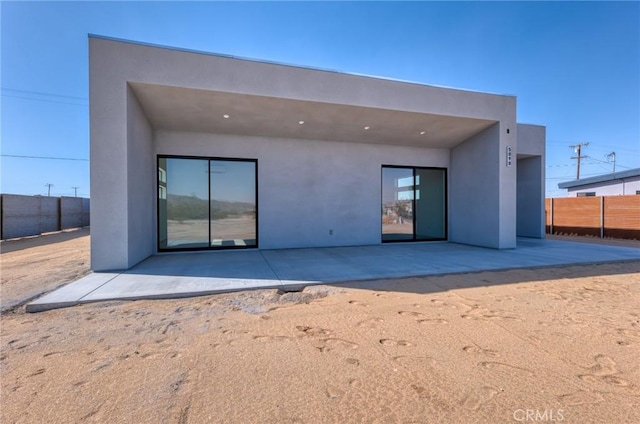 rear view of house featuring fence, a patio, and stucco siding