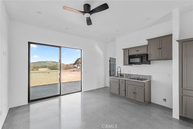 kitchen featuring concrete flooring, black appliances, a sink, and gray cabinetry