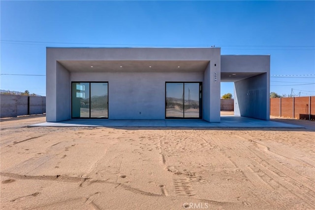 rear view of property featuring fence and stucco siding