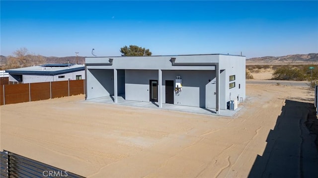 view of front of property featuring fence, a mountain view, and stucco siding