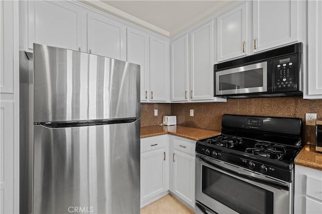 kitchen with dark stone countertops, stainless steel appliances, and white cabinets