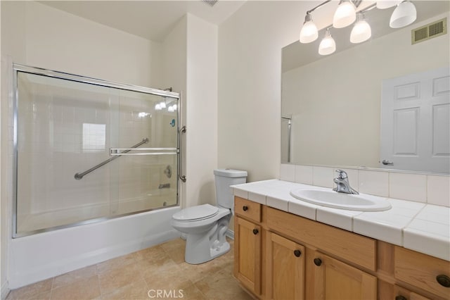 full bathroom with visible vents, combined bath / shower with glass door, toilet, and vanity