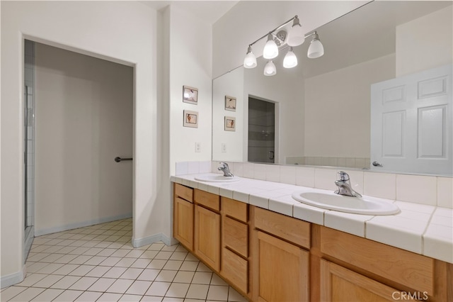 full bathroom with a sink, baseboards, double vanity, and tile patterned floors