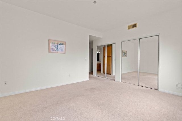 unfurnished bedroom with visible vents, two closets, baseboards, and carpet floors