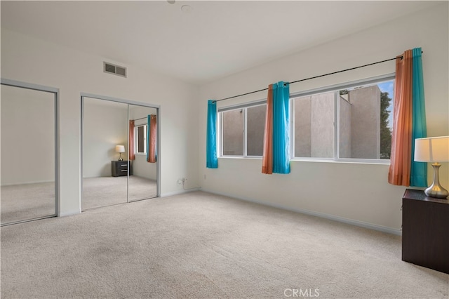 unfurnished bedroom featuring baseboards, visible vents, multiple closets, and carpet floors