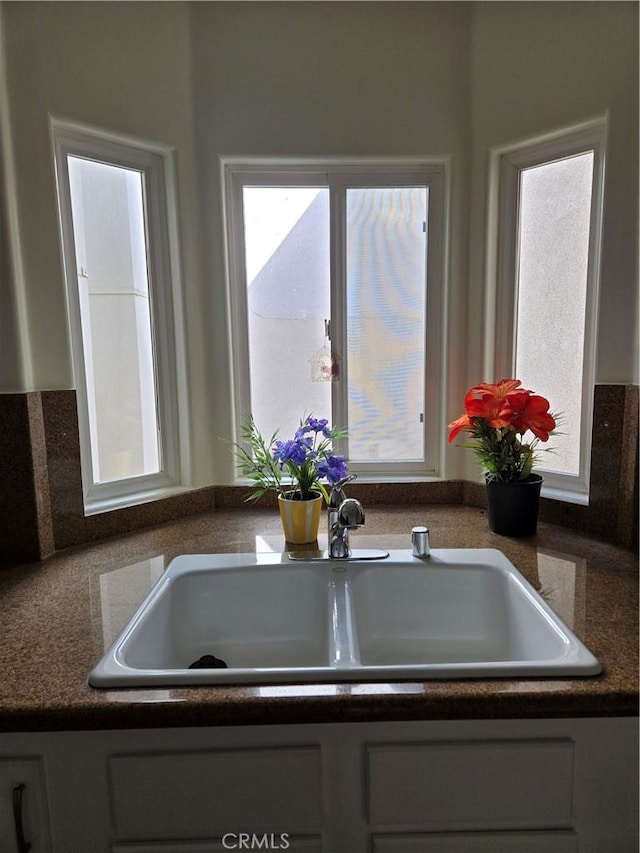 kitchen with a sink, dark countertops, and a wealth of natural light