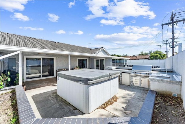 view of patio featuring a hot tub, fence, an outdoor kitchen, and area for grilling