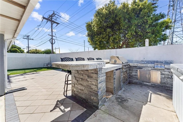 view of patio featuring outdoor wet bar, a fenced backyard, a grill, and area for grilling