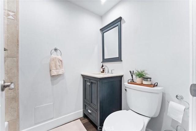 full bathroom featuring toilet, wood finished floors, vanity, baseboards, and walk in shower