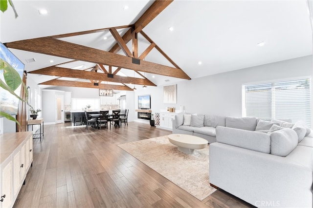 living room featuring light wood-style floors, high vaulted ceiling, beam ceiling, and recessed lighting