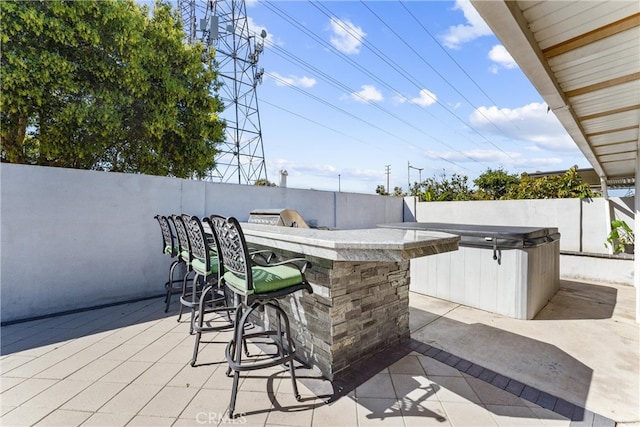 view of patio featuring a fenced backyard, outdoor wet bar, and a hot tub