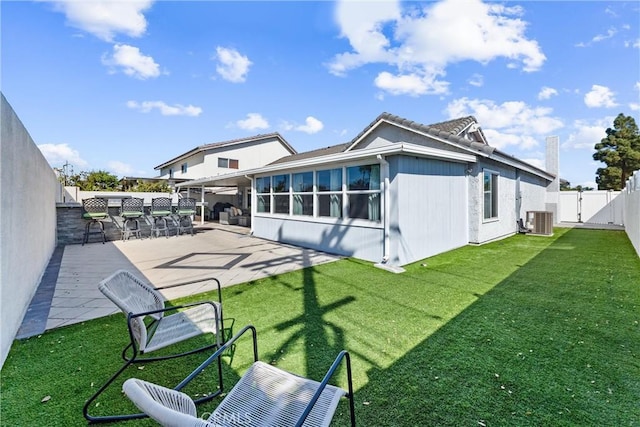 back of property with outdoor dry bar, a patio, a lawn, and a fenced backyard