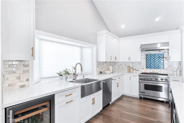 kitchen featuring beverage cooler, white cabinets, wall chimney exhaust hood, appliances with stainless steel finishes, and a sink