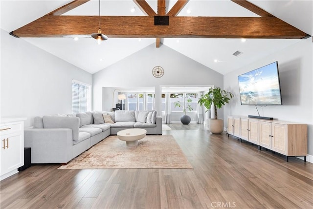 unfurnished living room featuring visible vents, high vaulted ceiling, wood finished floors, and beam ceiling