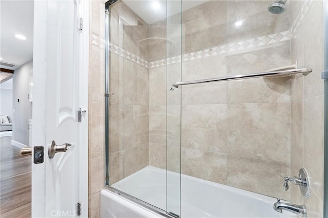 full bathroom featuring bath / shower combo with glass door and wood finished floors