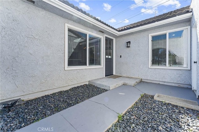 entrance to property featuring a tiled roof and stucco siding