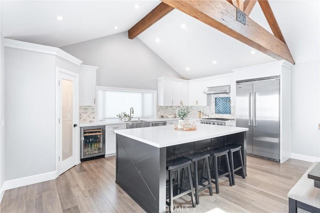 kitchen featuring beverage cooler, white cabinets, beamed ceiling, ventilation hood, and stainless steel built in refrigerator